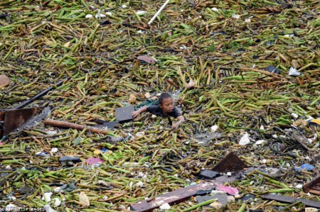Un jeune enfant nage dans les débris après une tempête tropicale à Manille